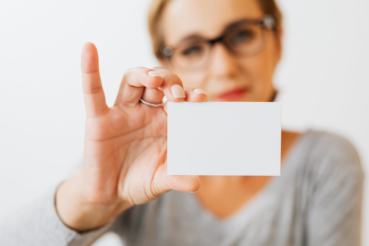 Close-up of a woman holding a blank business card with a blurred background for copyspace.