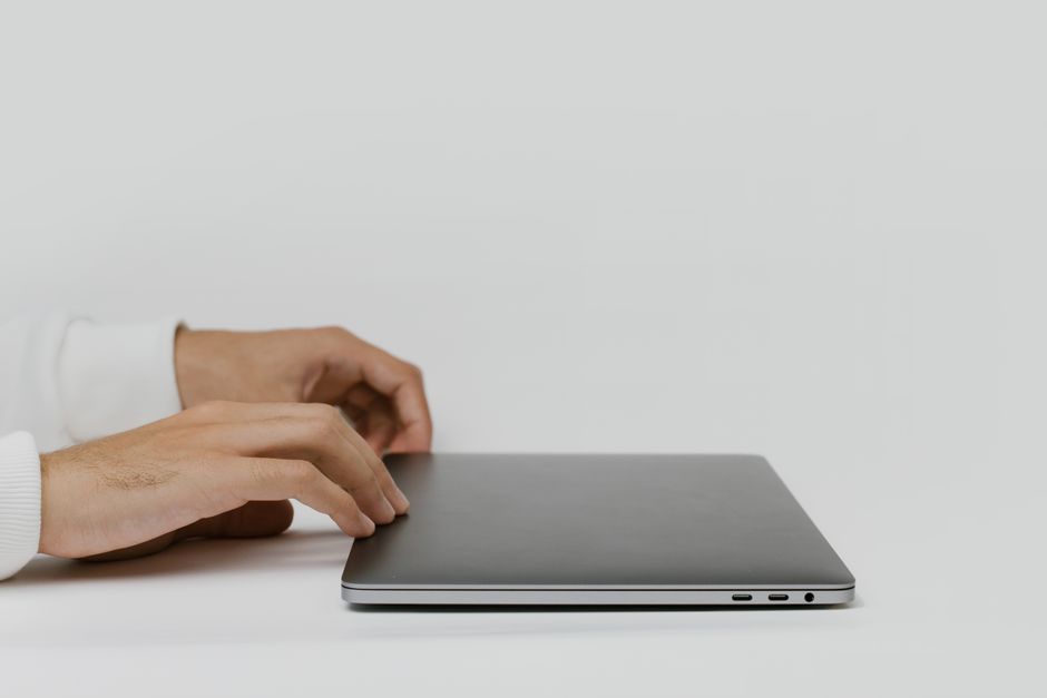 INICIO Hands preparing to open a closed laptop on a minimalist desk, ready for work.